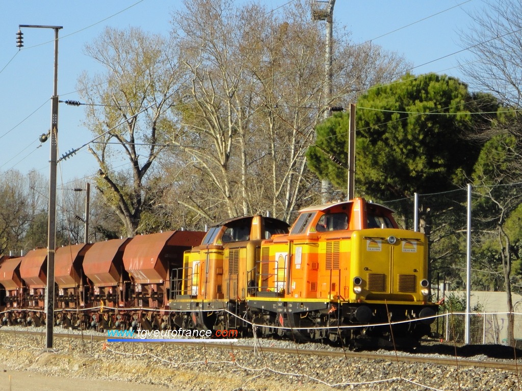 Vue détaillée des deux locomotives thermiques V100 tractant des wagons de transport de ballast