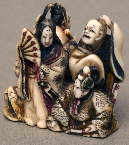 005-Marfil netsuke con detalles de color. Representa un grupo de cinco mandarinas acompañados de una geisha que sostiene un abanico-Bolton Museum and Archive Service