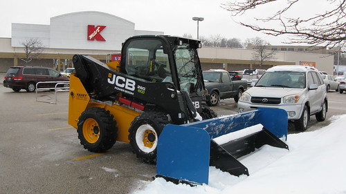 A small Caterpillar 4 wheel front end loader tractor equipped with a snowplow.  Des Plaines Illinois.  Monday, February 4th, 2013. by Eddie from Chicago