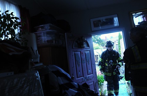 Firemen arrive to check out the source of the burning smell, pile of clean clothes taken from the moldy closet due to the leaking roof, substandard housing, Broadview Duplex, Seattle, Washington, USA by Wonderlane