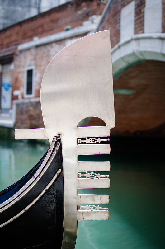 A gondola ornament at rest along a small canal in Venice. 