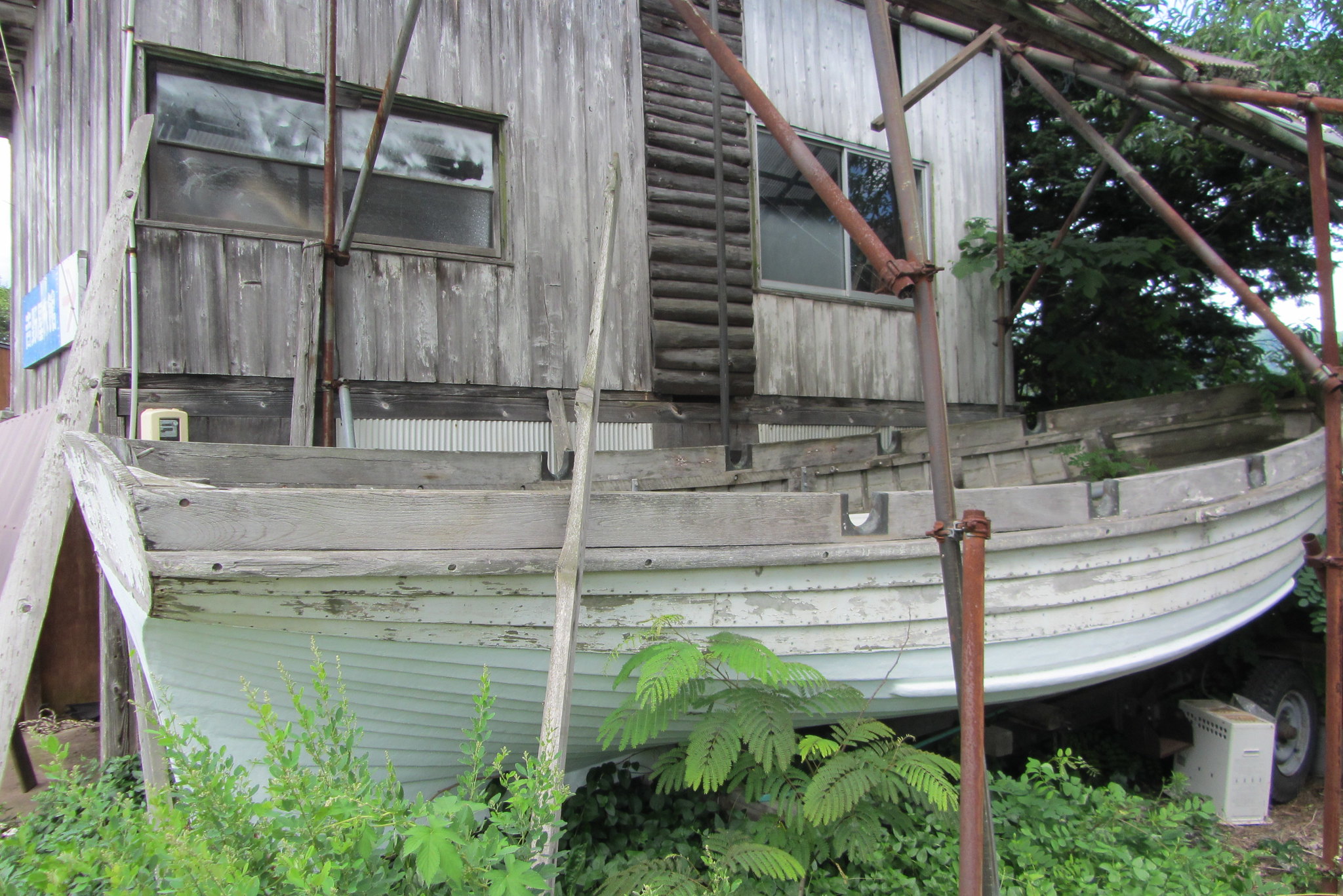 Old wooden rowboat by wooden house | Old wooden rowboat by w 
