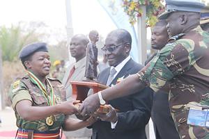 President Mugabe hands over the Mbuya Nehanda trophy to Sergeant Evelyn Fimba who was the overall winner in the women’s category of the President’s Medal Shoot competition while Air Force of Zimbabwe commander Air Marshal Perrance Shiri looks on. by Pan-African News Wire File Photos