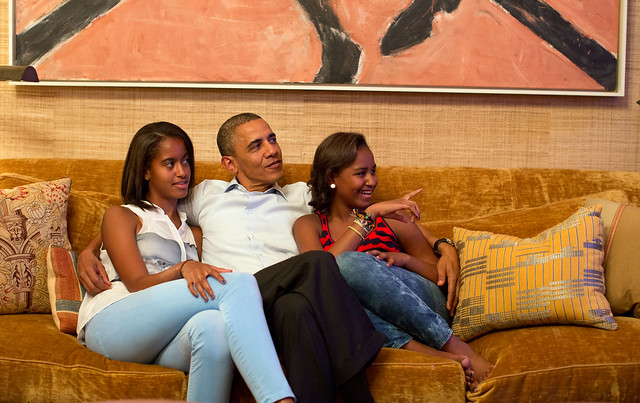 image of President Obama and his daughters sitting cuddled on a couch together, looking nervous, proud, excited