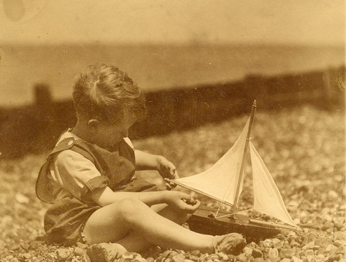 Child on the beach with a toy boat