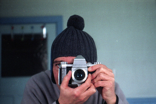 reflected self-portrait with Praktica IV camera and knitted hat by pho-Tony