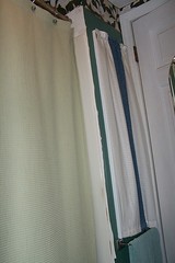 Mismatched curtains covering things in the bathroom. This room is a total ugly mess.