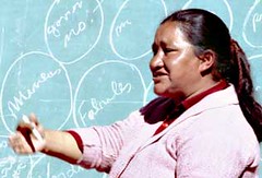 Domitila Barrios de Chungara speaking in pink sweater in front of chalkboard