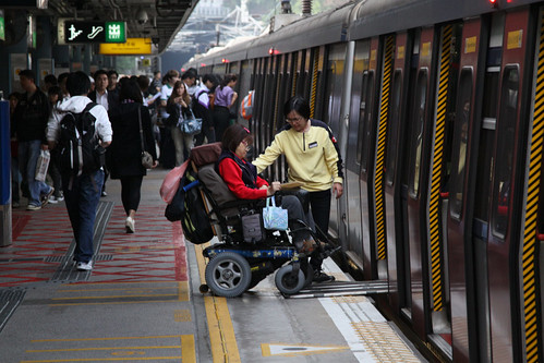 MTR staff assist a wheelchair bound passenger onboard a train