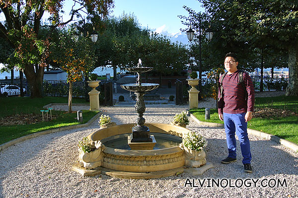 Me standing beside a fountain just in front of the hotel facing Lake Geneva