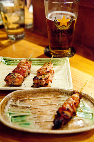 Chicken thigh with yuzukosho skewers (center), chicken rib (foreground) and Sapporo beer
