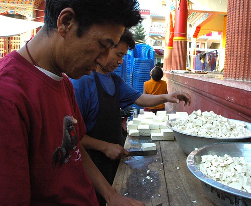 Two Tibetan cooks diceing tofu for vegetarian food into aluminum bowls, on a makeshift cutting counter, celebration tsok (meal), Sakya Lamdre, Tharlam Monastery stage, Boudha, Kathmandu, Nepal by Wonderlane