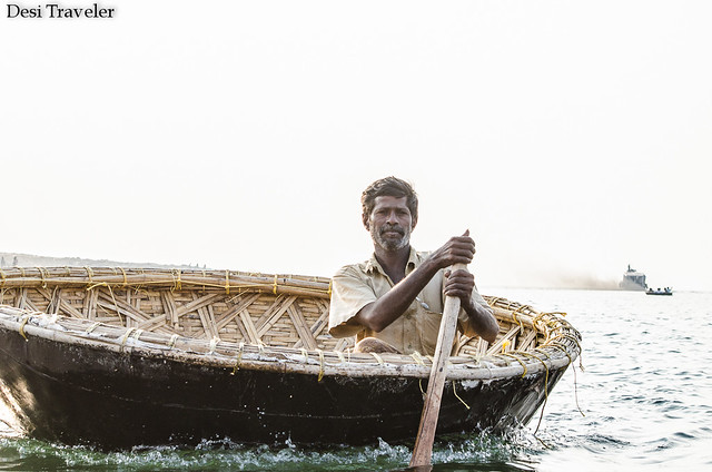 a boatman poses for picture in his coracle or round boat 
