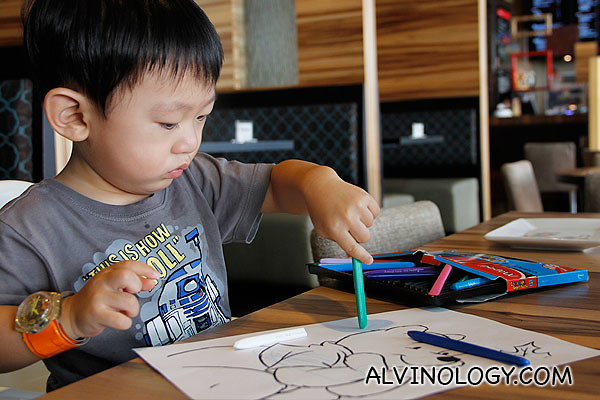 Asher colouring with crayons on paper, with material provided by the nice staff at Charly T 