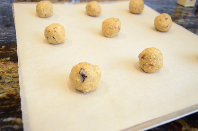 Balls of cookie dough arranged on a cookie sheet lined with parchment paper.
