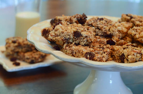 Cherry Dark Chocolate Granola Bars on a display dish, with a glass of milk in the background.
