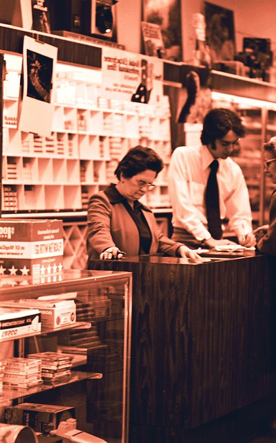 A red-tinged photo of a man and woman clerk studying something on the counter