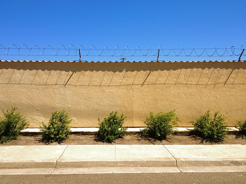 street city blue shadow urban wall fence landscape golden wire industrial view neighborhood sidewalk barrier barb stockton squiggle razor protect keepout notwelcome