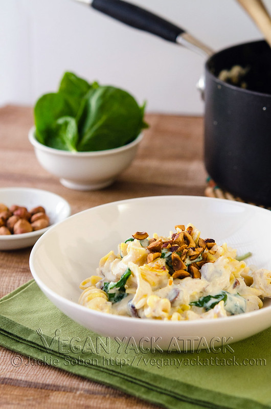 creamy pasta in a white bowl topped with toasted hazelnuts