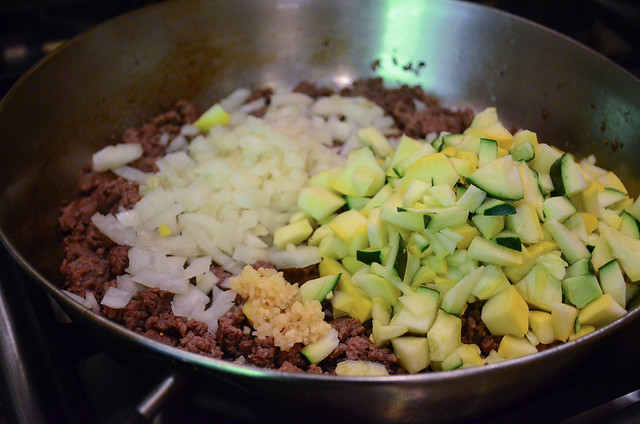Ground beef cooking in a skillet combined with the chopped veggies.