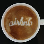 A coffee mug with the word 'AirBNB' written in cream.