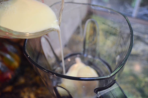 Milk being poured into a blender, over the frozen bananas.