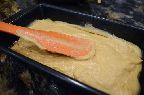 A silicone spatula smoothing out the batter in a loaf pan.