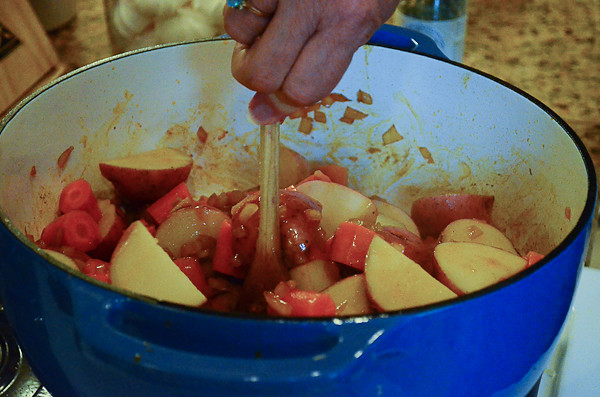 The pot of ingredients being stirred after potatoes have been added.