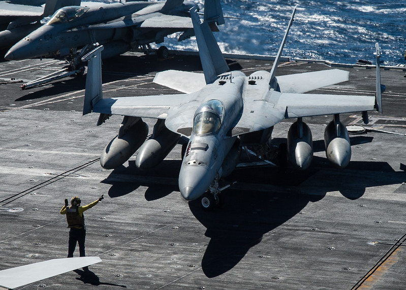 A Sailor directs an F/A-18E Super Hornet.