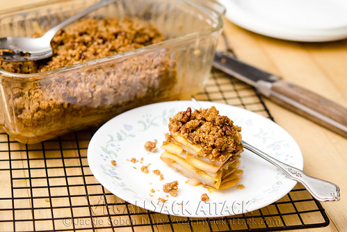 Slice of apple pear crisp on a plate, next to casserole dish on a cooling rack