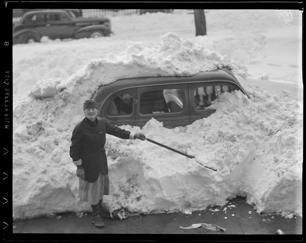 Woman digs out snow covered auto