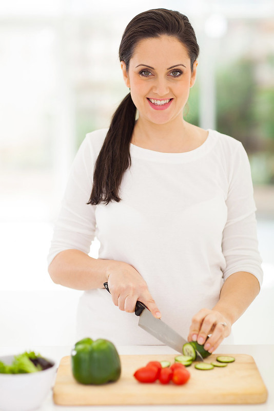 portrait of pregnant woman cutting vegetables