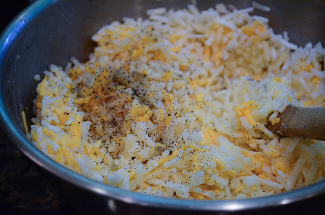 A the hash brown ingredients being mixed in a bowl.