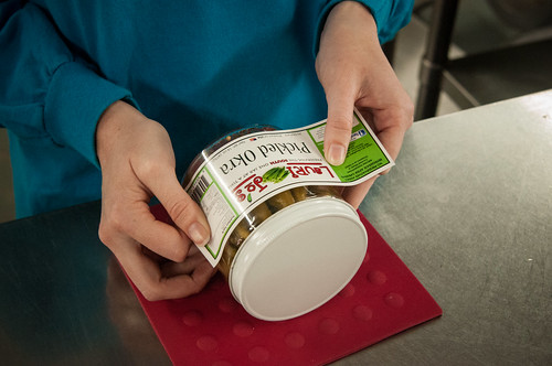 Laurie Jo’s Southern Style Canning business owner’s daughter Mikelyn Bennett applying labels to pickled okra packaged at her mother’s business.