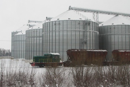 Tiny 0-4-0 diesel shunter at work beside a modern grain silo in Ukraine