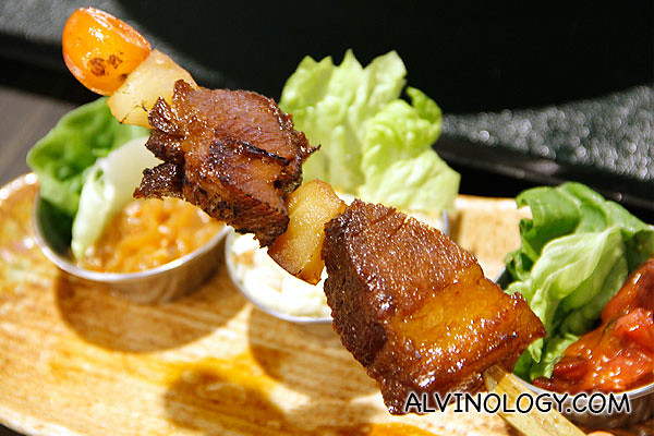 Teriyaki pork belly skewer and three sides in the background 