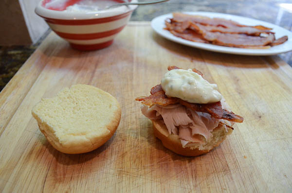 A slider being assembled with turkey, bacon, and ranch/Gorgonzola.