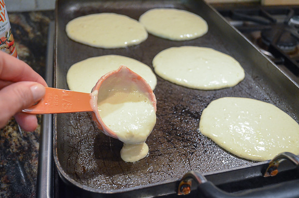 Pancake batter being poured onto a hot pan.