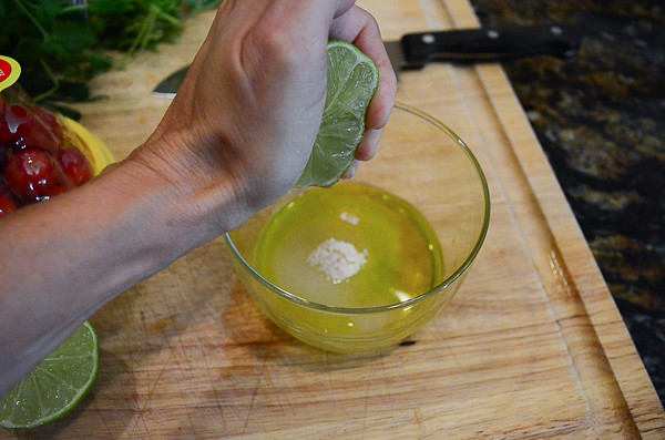 A hand squeezing a lime into a container.