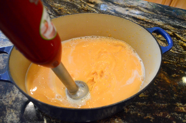 An immersion blender is blending the ingredients into a puree.