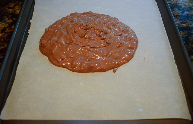 The melted chocolate is poured on a parchment lined baking sheet.