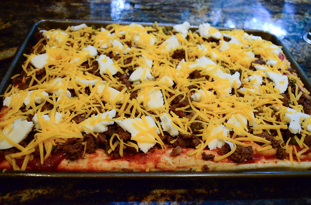 Cheddar cheese is added to the top of the pizza.