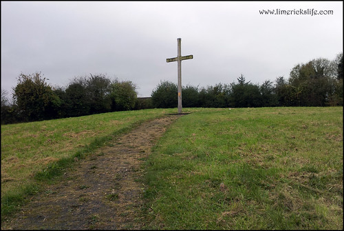 Path worn through grass going upwards to large wooden cross at St Bridget's Graveyard