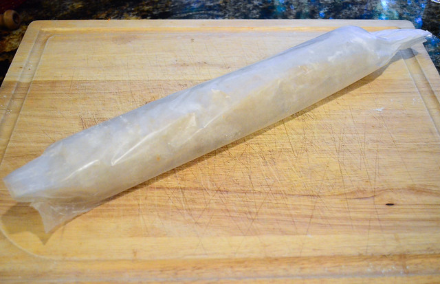 Wax paper is rolled around the cookie dough.