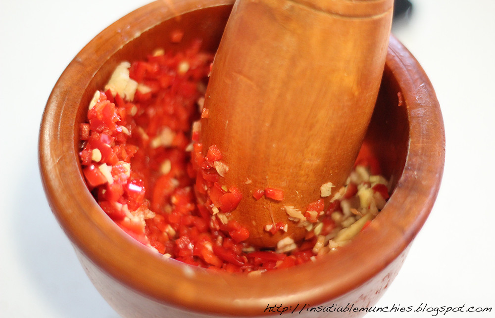 pounding the chilli into a fine paste using a mortar and pestle