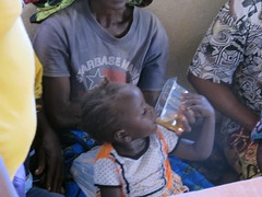 Child drinking ORS solution from the Kit Yamoyo container (and measure)