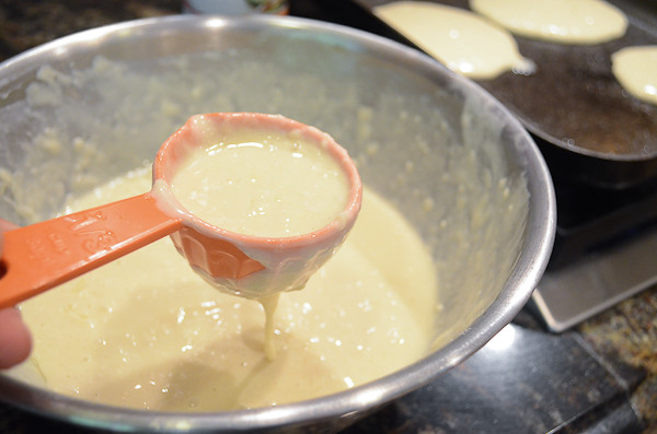 A measuring cup scooping out pancake batter.