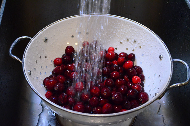 Cranberries being washed in a colander.