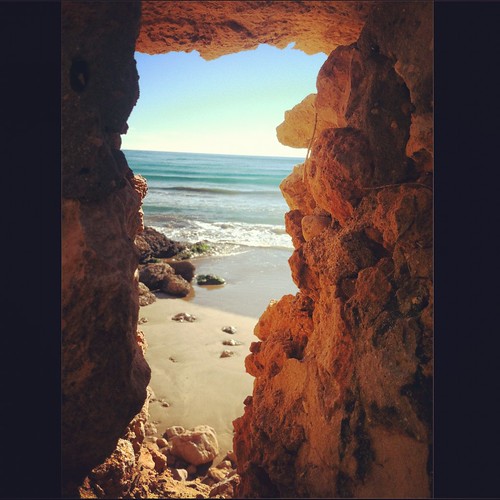 beach sand rocks waves view hole peep cave crevice