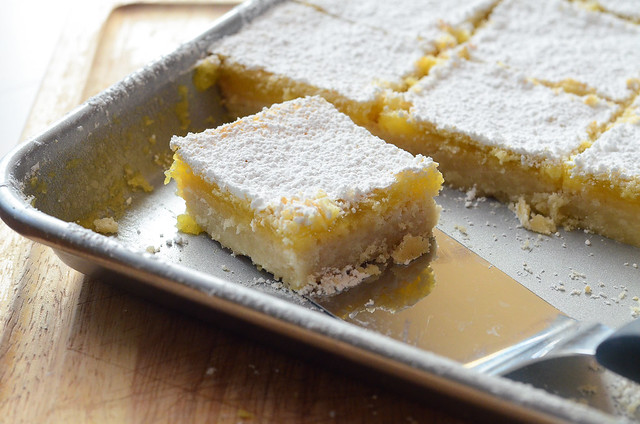 A lemon bar about to be lifted by a spatula.